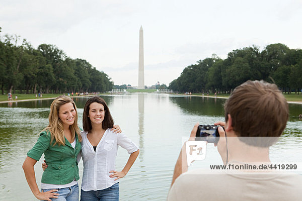 Junger Mann fotografiert Freunde am Washington Monument.