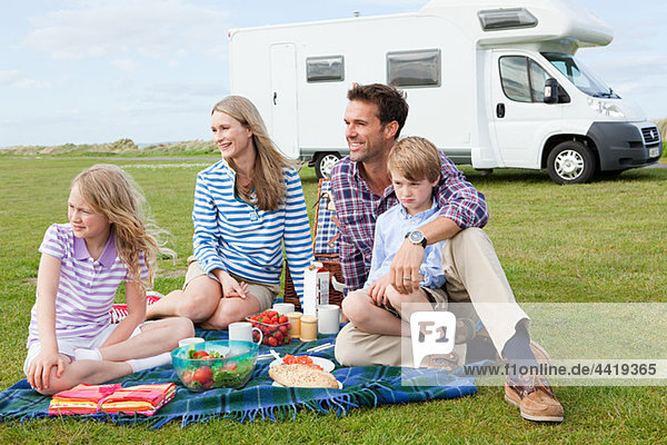 Family having picnic by caravan