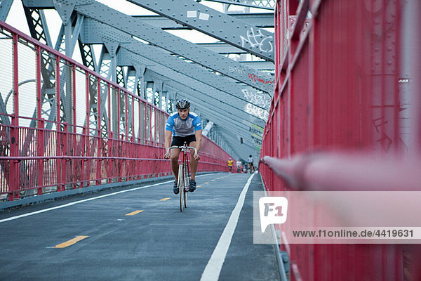 Mann radelt über Brücke
