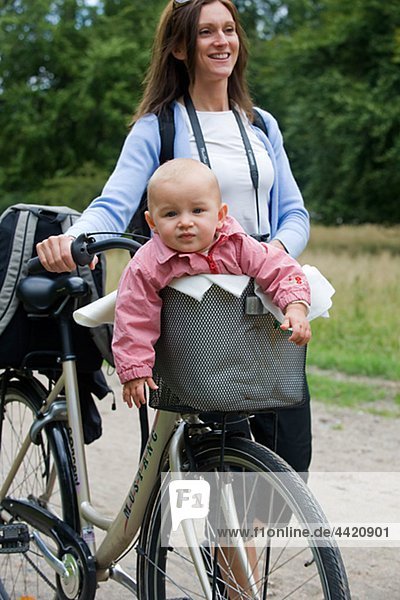 Mutter drängen Fahrrad mit Baby in Gepäcktasche