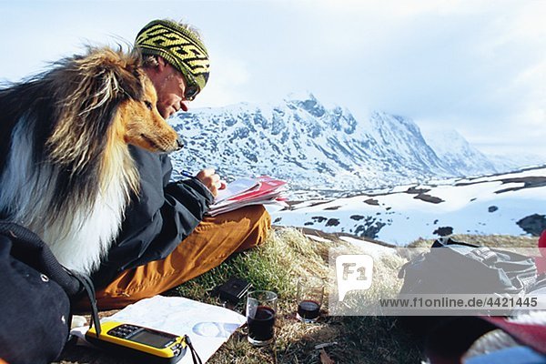 Man with dog writing in mountain scenery