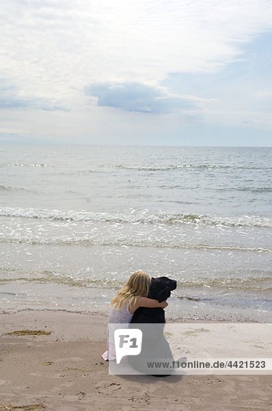 Mädchen mit Hund am Strand sitzen