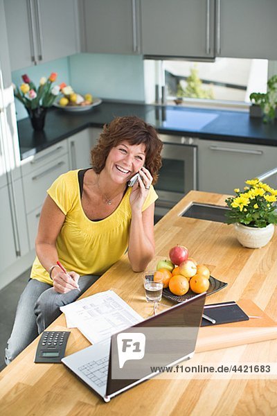 Frau sitzend mit Rechnungen und sprechen auf Handy