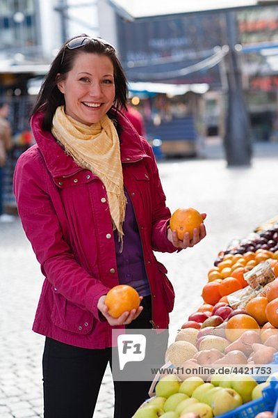 Junge Frau Orangen auf Obstmarkt auswählen