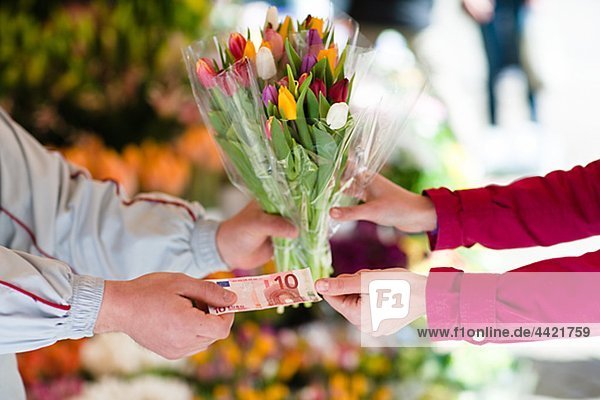 Person buying bunch of flowers from vendor
