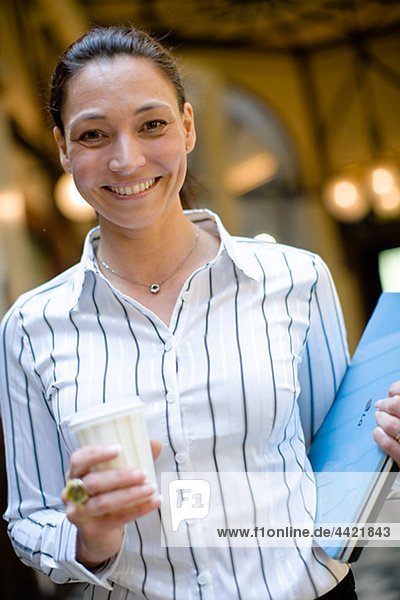 Porträt von Reifen geschäftsfrau hält Takeaway Kaffee in einer Hand und Datei in einem anderen