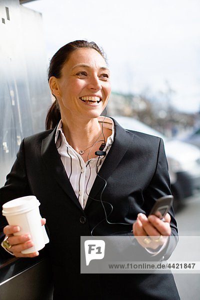 Fröhlich geschäftsfrau mit Takeaway Kaffee in einer Hand und Handy in einem anderen