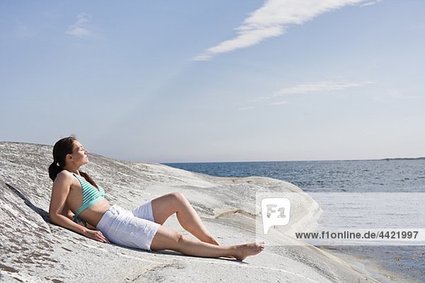 Frau liegend auf Felsen auf dem Seeweg