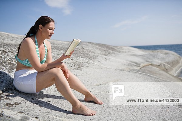 Frau sitzen auf Rock und Buch