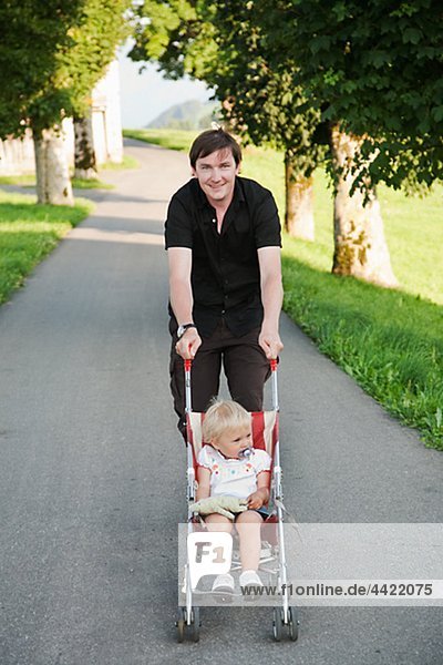 Vater Tochter in Kinderwagen im Park zu tragen
