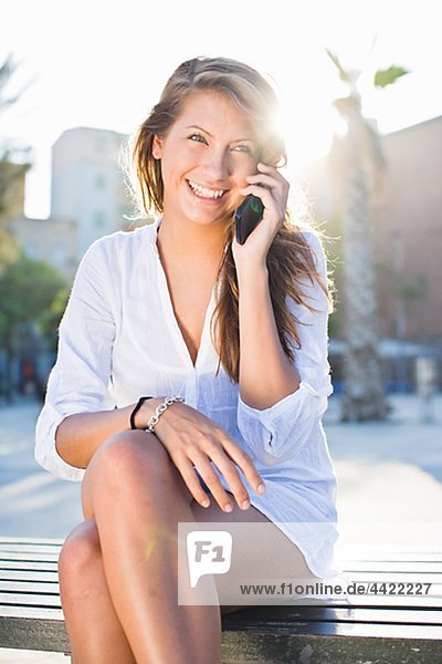 Junge Frau sitzend auf Parkbank  sprechen auf Handy
