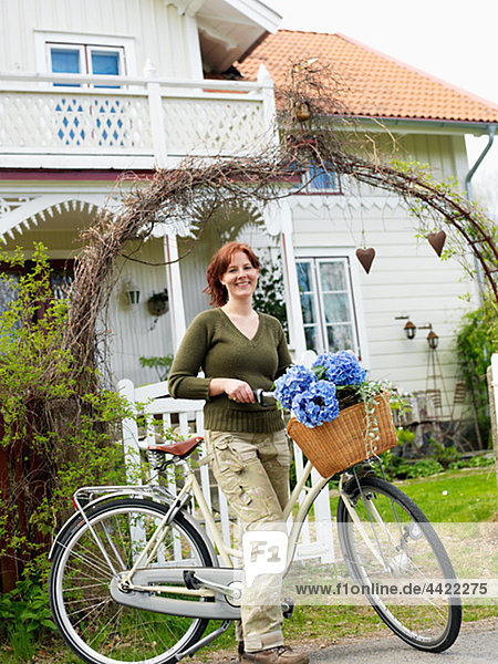 stehend Frau Wohnhaus lächeln frontal Fahrrad Rad