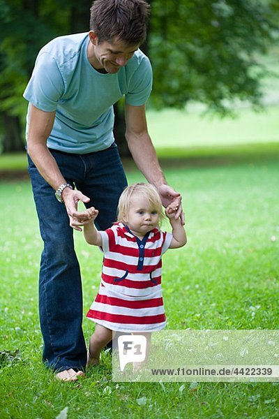 Mid adult father helping daughter with first steps