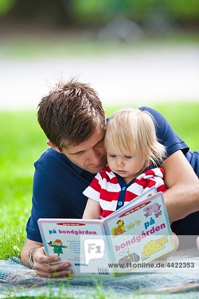 Mid adult father embracing daughter and reading her book