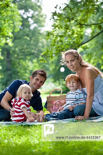 parents with children sitting in park and looking at camera