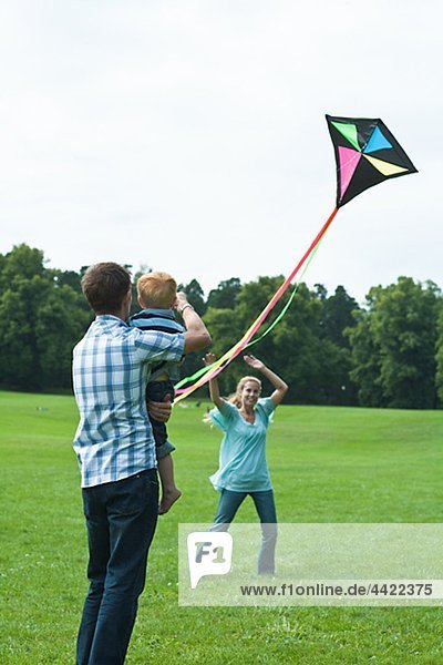 Eltern und Sohn spielen mit Kite im park