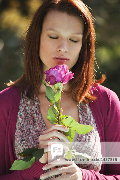 Young woman smelling rose