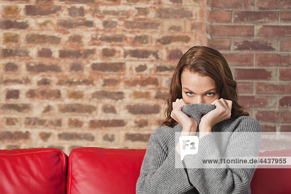 Young woman hiding her face with sweater