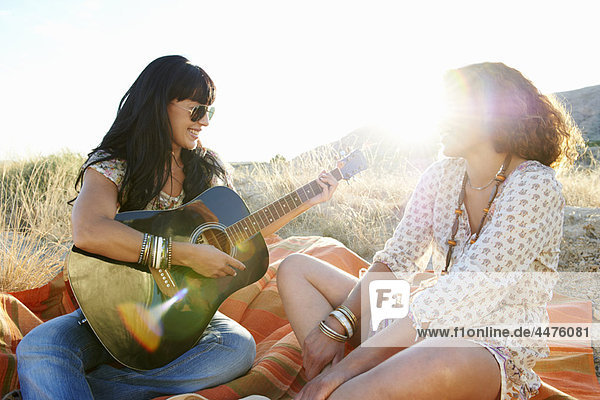 Women playing the guitar in the grass