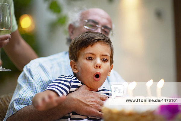 Kind beim Ausblasen von Kerzen auf einem Kuchen
