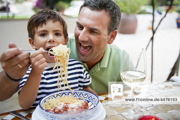 Father and son eating spaghetti