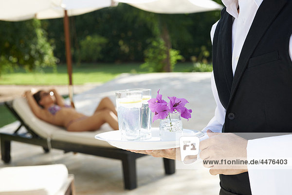 Hotel waiter holding tray by hotel pool