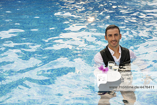 Waiter with a trey of drinks in a pool