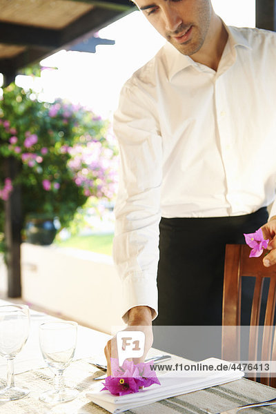 Waiter laying dinner table in hotel