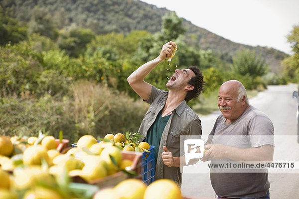 Men squashing oranges