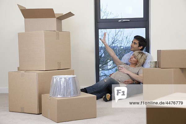 Couple sat amongst boxes in apartment