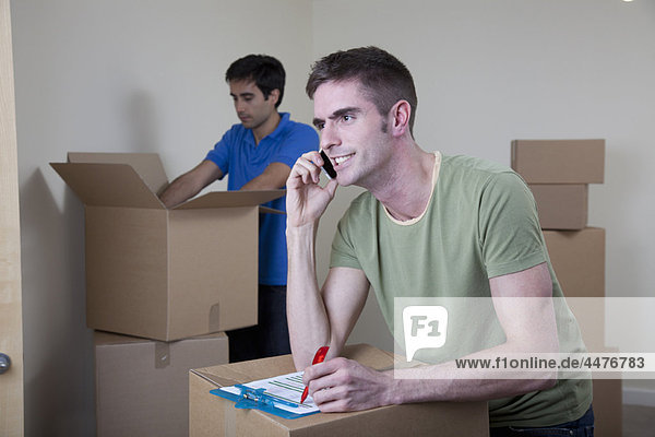 Two men unpacking boxes in apartment