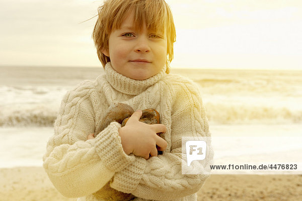 Kleiner Junge an einem Strand mit Steinen