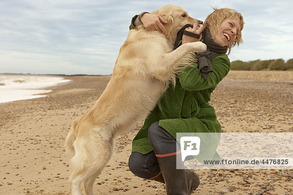 Woman training  playing with dog  beach