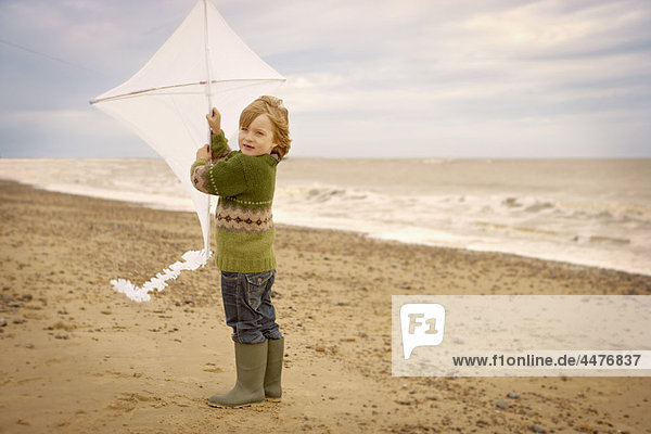 Kleiner Junge am Strand mit Drachen. Herbst