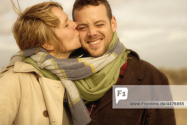 Frau küsst Mann am Strand Schals gemischt