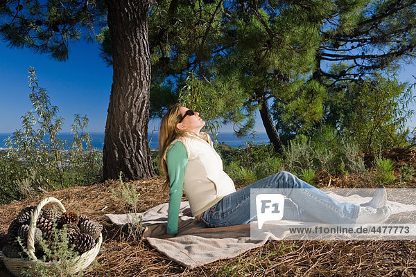 Frau auf Decke entspannt in ländlicher Umgebung