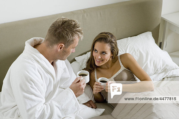 Junges Paar trinkt Kaffee im Bett