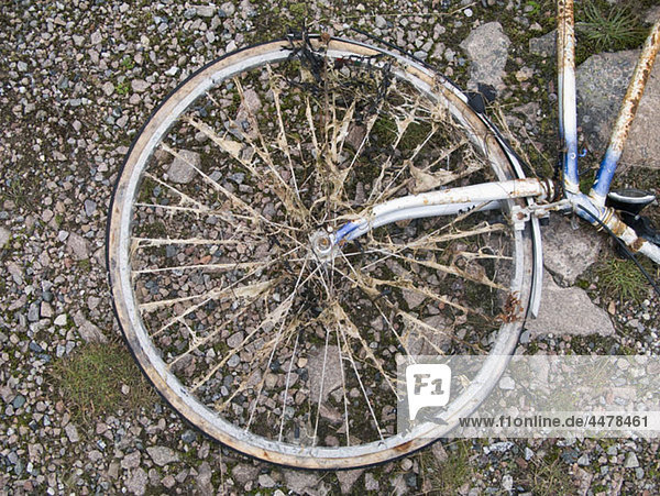 Teil eines alten Fahrrads  das auf dem Boden liegt.