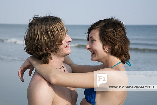 A young affectionate couple laughing at the beach