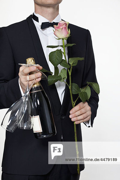 Ein Mann im Smoking mit Rose  Champagnerflasche und Champagnerflöte  Mittelteil