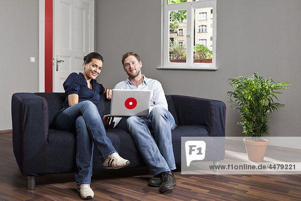 A young couple using a laptop together in their living room