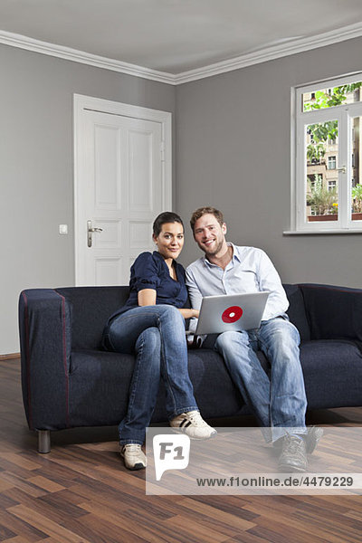 A young couple using a laptop together in their living room