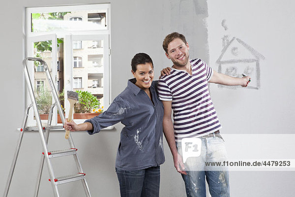 Ein junger Mann und eine junge Frau  die eine Wohnung renovieren.