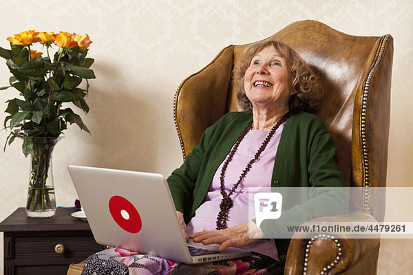 Eine lachende Seniorin mit einem Laptop.