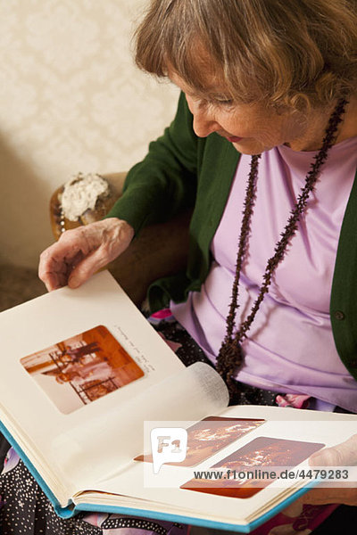 Eine ältere Frau  die durch ein Fotoalbum schaut.