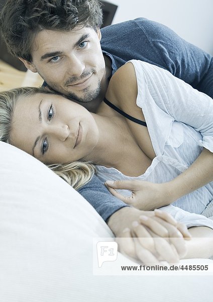 Affectionate young couple lying in bed