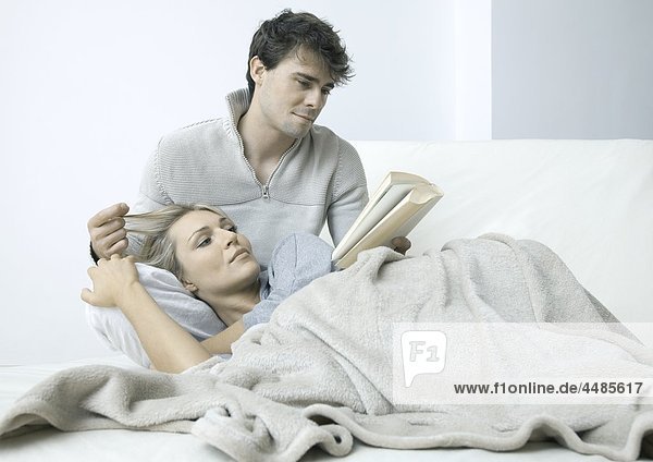Young couple on bed reading book