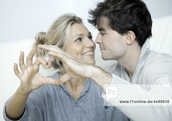 Young couple in love making heart with their hands