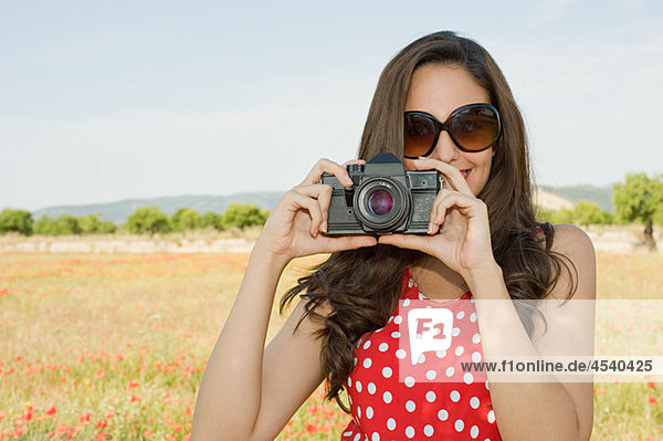 Young woman with camera in poppy field