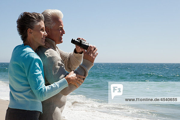 Mature couple at the beach with binoculars